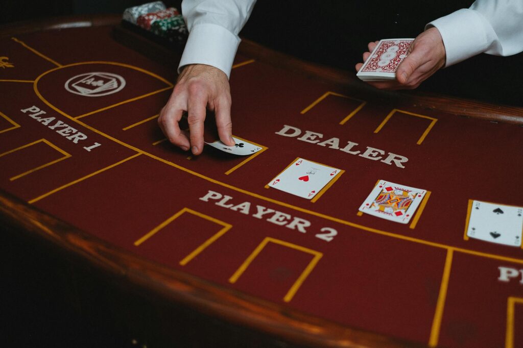 Close-up of a Blackjack table with players making bets and a dealer shuffling cards. — win at table games Las Vegas