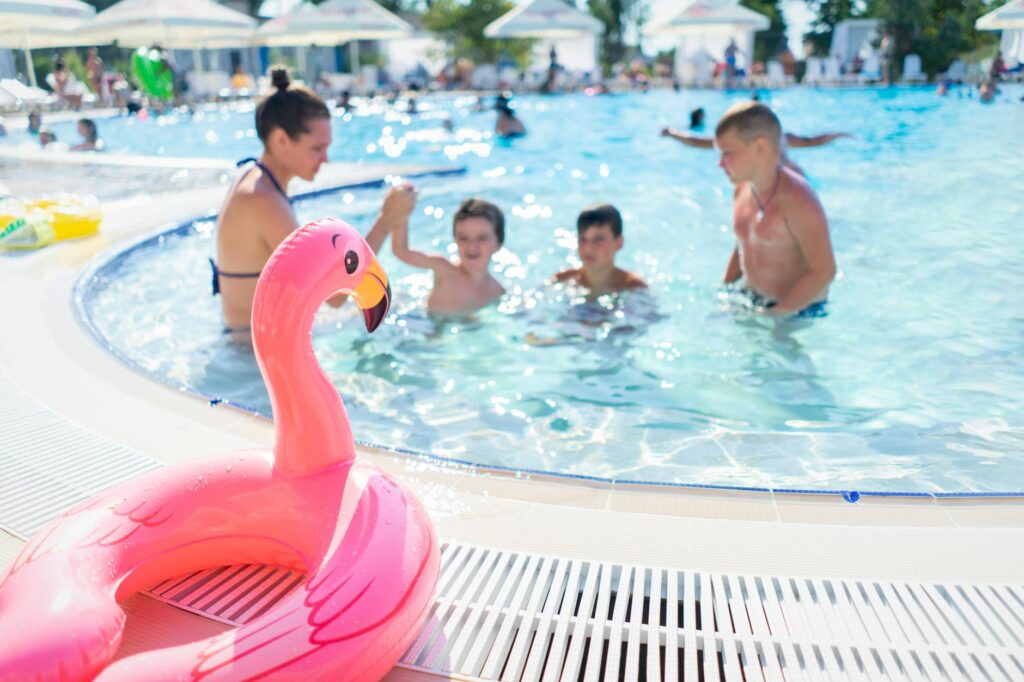 Kids splashing in a hotel pool, with parents relaxing nearby, highlighting family-friendly amenities. — family activitie…