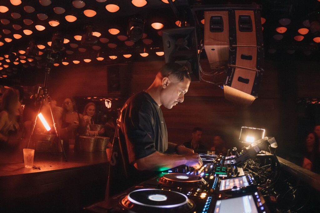 A DJ spinning records in a packed nightclub with a lively crowd. — Las Vegas nightclubs
