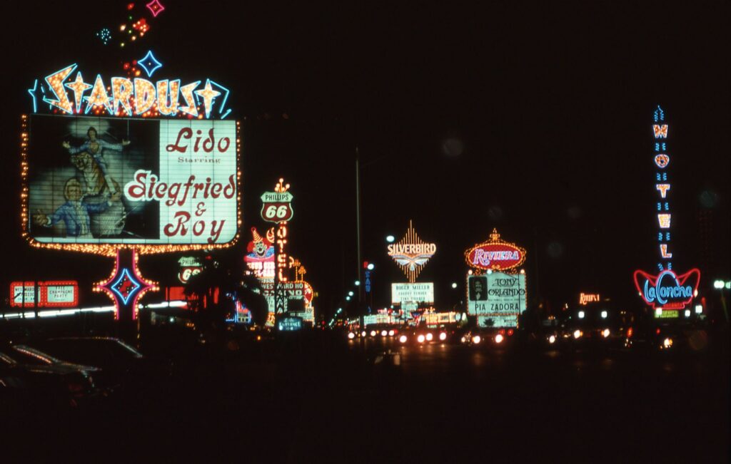 A bustling Las Vegas Strip at night, with bright lights and show billboards. — Las Vegas shows