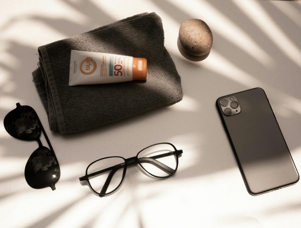 A close-up of travel essentials like sunscreen, sunglasses, and a water bottle — packing list Las Vegas