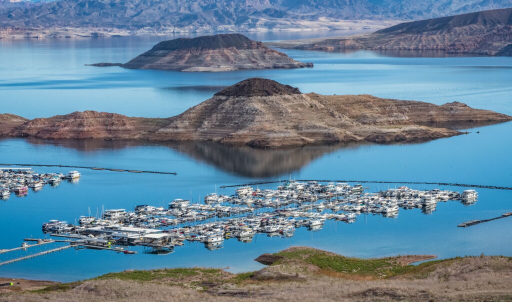 A serene scene of Lake Mead with boats on the water and mountains in the background. — las vegas day trips