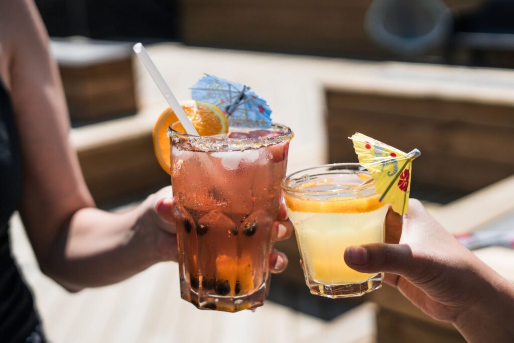 A close-up of a stylish cocktail served at a Vegas pool party, with a colorful umbrella and fruit garnish. — Las Vegas p…