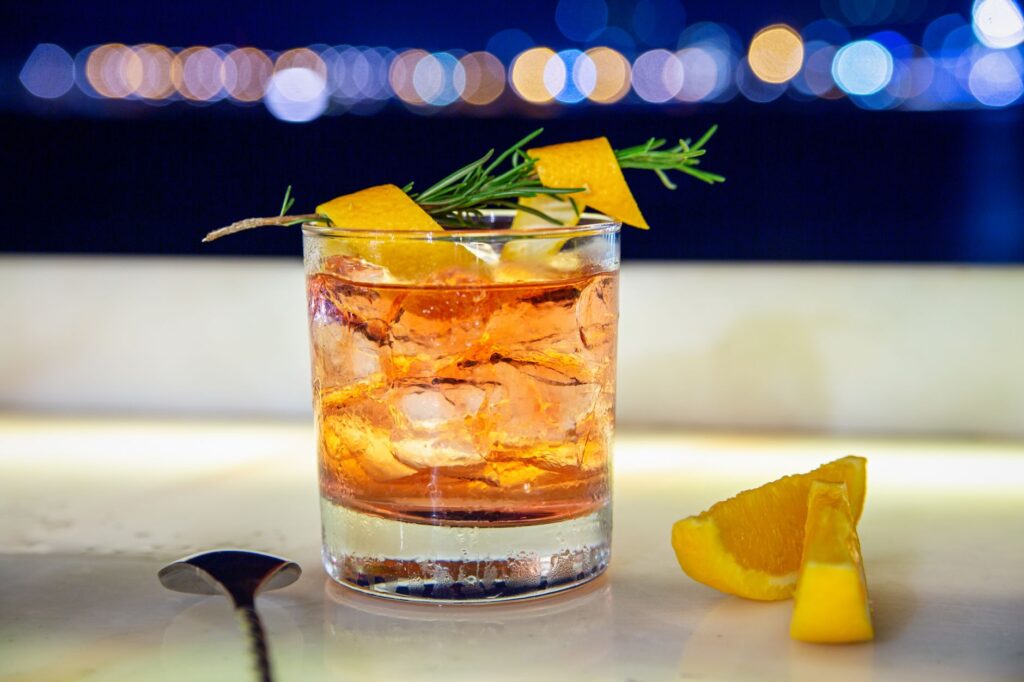 A close-up of signature cocktails served at The STRAT SkyPod against the backdrop of the city lights. — rooftop bars Las…