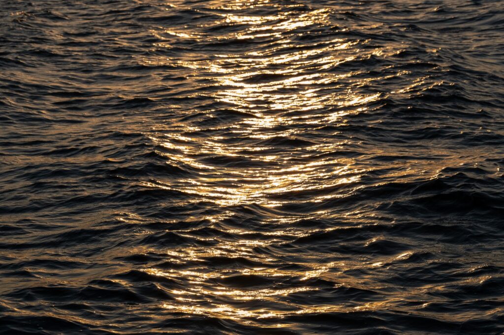 A serene view of Lake Mead at sunset, with the sun's reflection shimmering on the water. — las vegas sunset spots