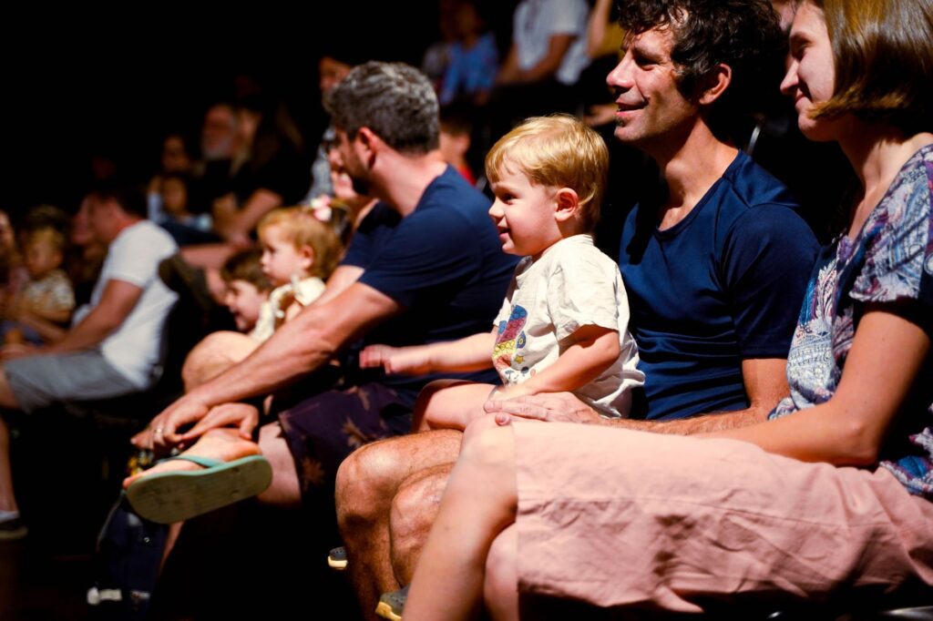 A family sitting in front of a kid-friendly Vegas show, excited and engaged. — family-friendly activities Las Vegas