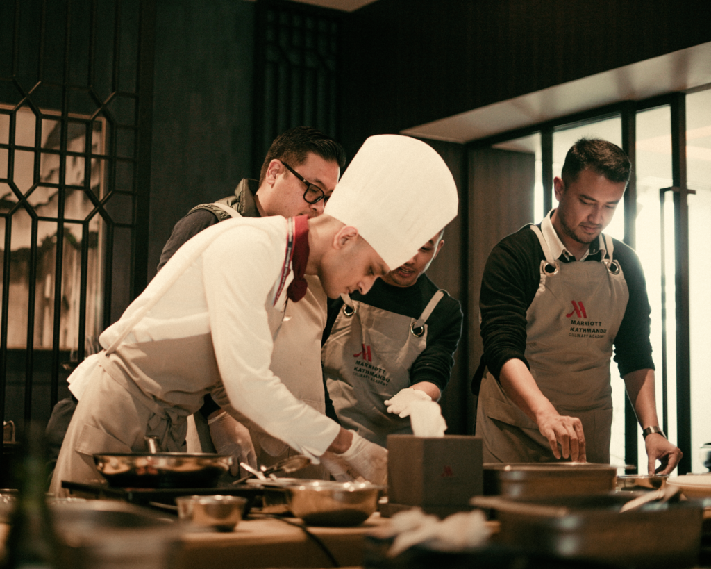 Guests participating in a cooking class at a restaurant, engaged in hands-on cooking with chefs. — unique dining Las Vegas