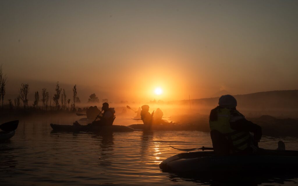 A family kayaking on Lake Mead with the sun setting in the background. — outdoor adventures Las Vegas