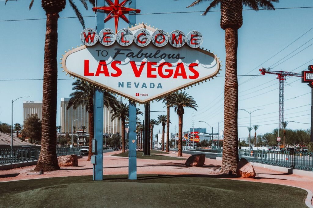 A tourist posing in front of the Welcome to Fabulous Las Vegas Sign, highlighting budget attractions Las Vegas.